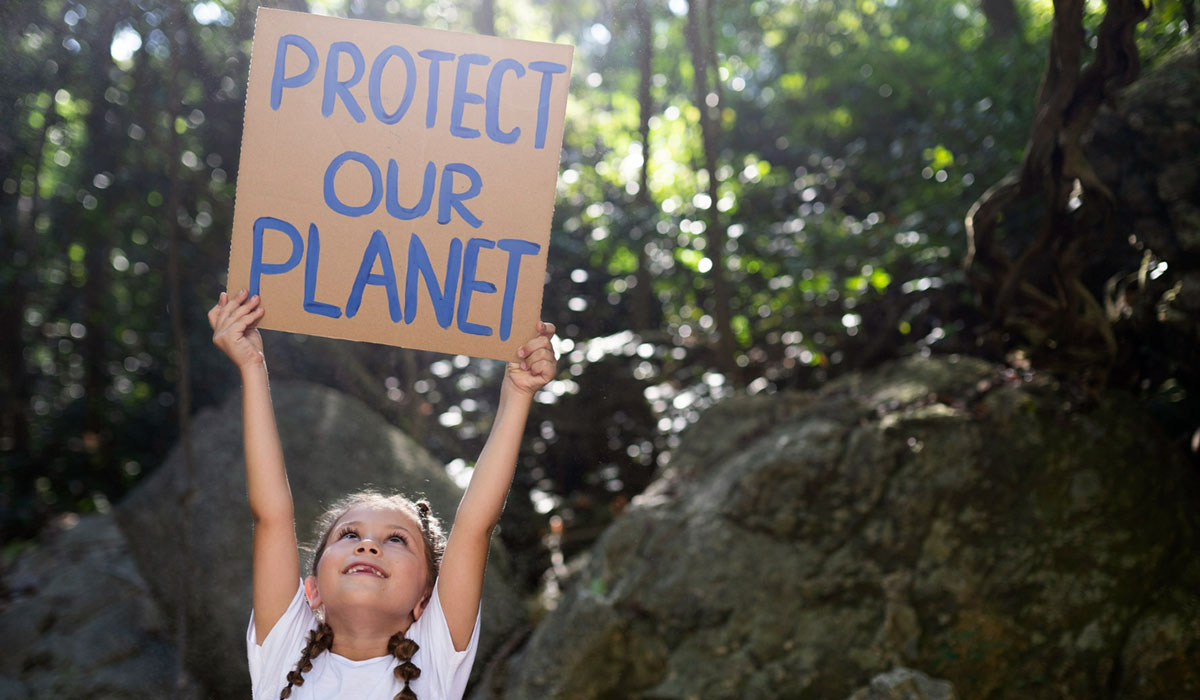 Kind hält Plakat hoch: Protect our planet