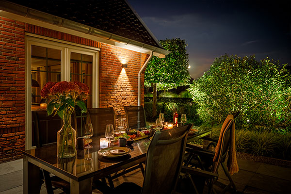 Tisch mit Stühlen beleuchtet vor Haus